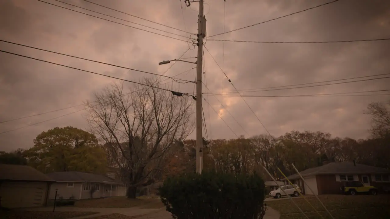 A telephone pole in the center of a dreary orange sky before an intense Autumn Storm