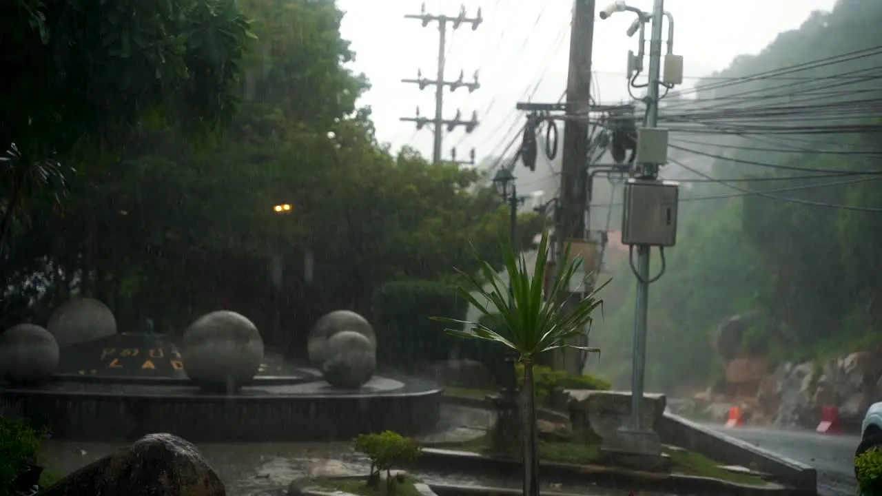 Huge downpour in the rainy season in Thailand creates large puddles on the ground while a scooter rides on the road