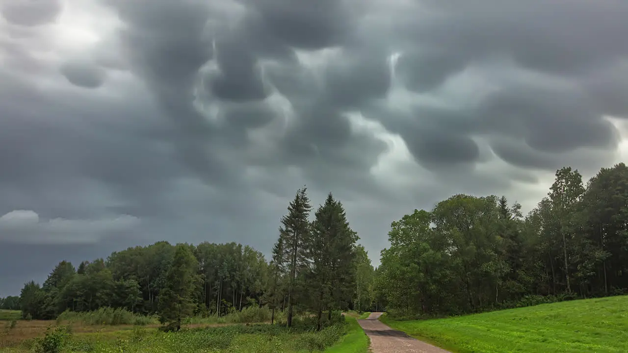 Time Lapse of Dark Rainy Clouds Moving Above Green Forest and Countryside Road