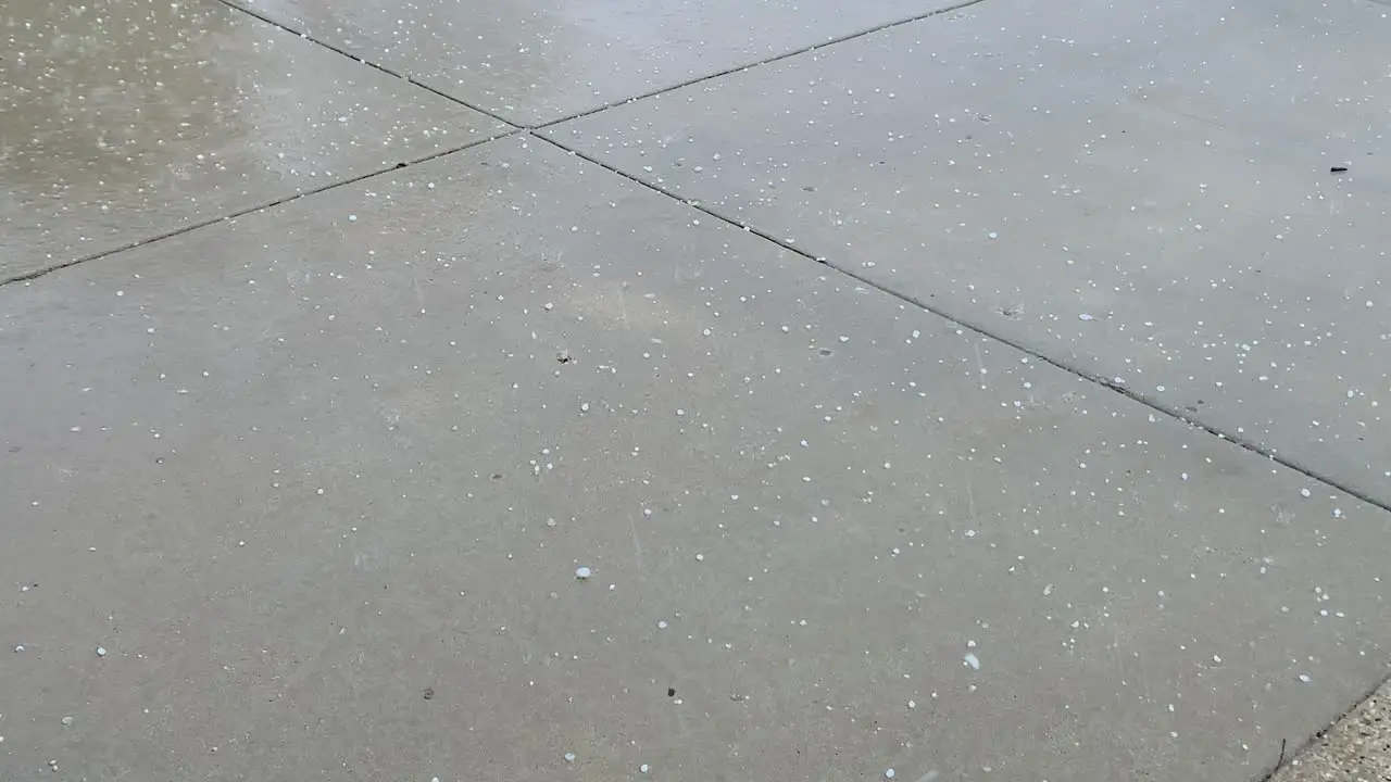 Hail during rainstorm on a driveway close up