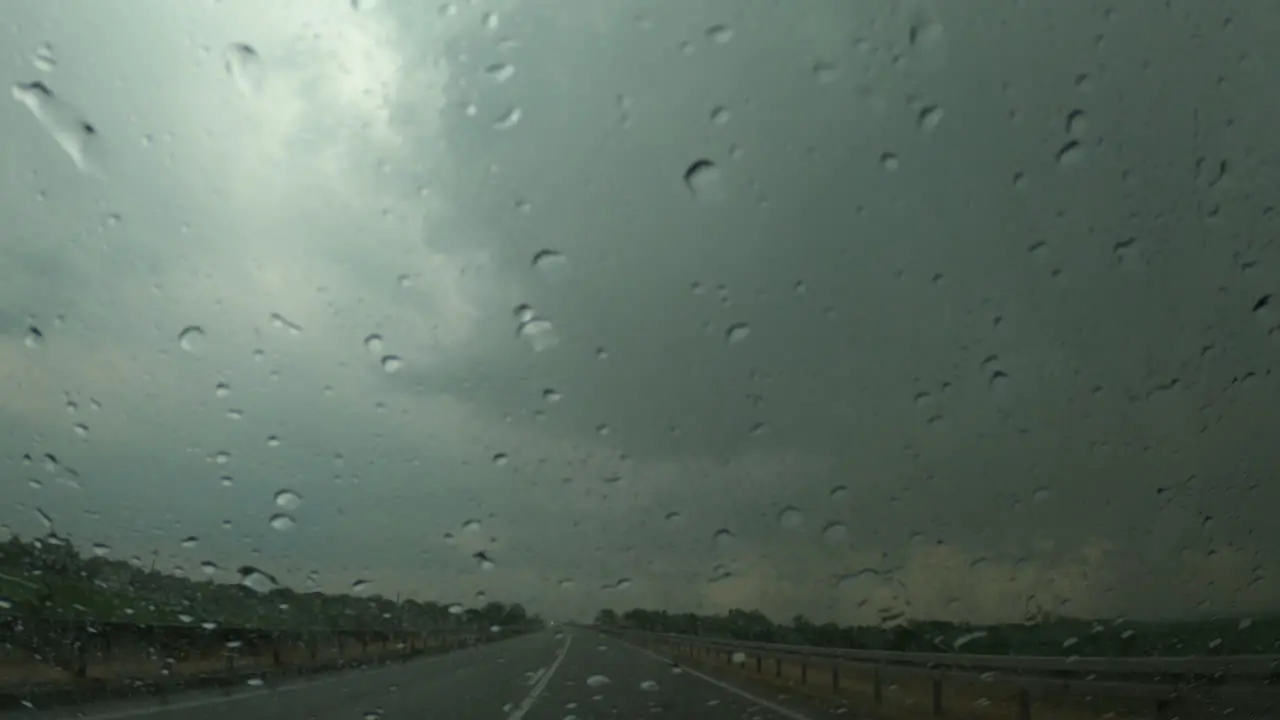 Raindrops on car windscreen during severe summer storm rain rainy season on highway