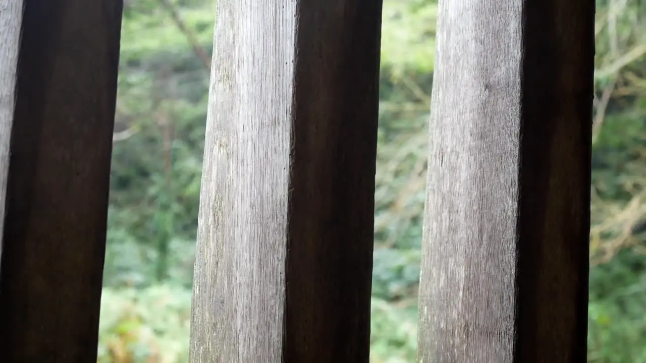 Raining weather in rural mountain countryside through rustic oak wood barn beams window dolly left shot