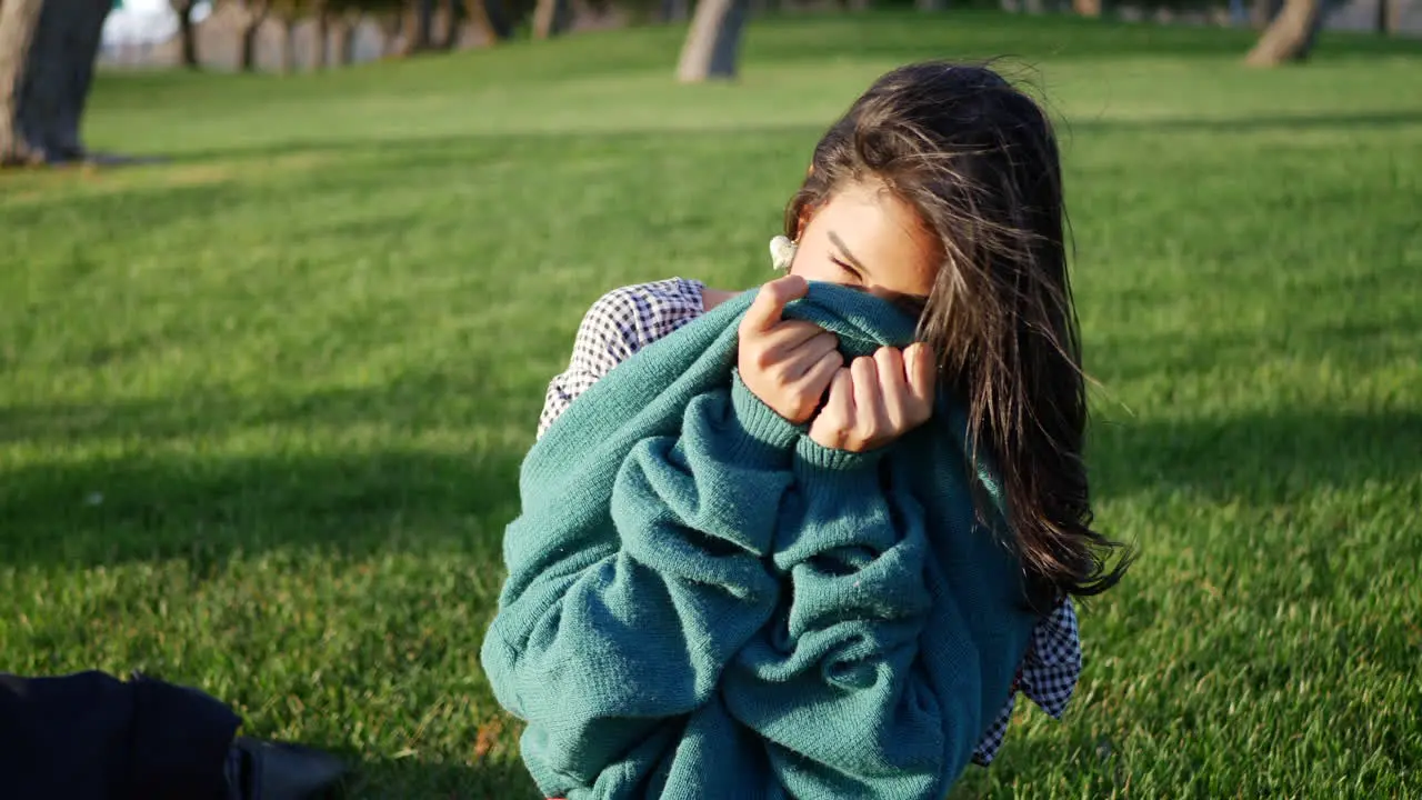 Close up of a pretty hispanic woman trying to get warm and cozy with her sweater in cold season windy weather