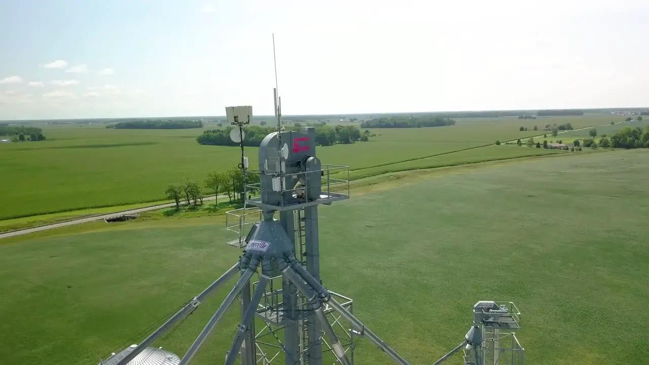 Aerial view orbiting weather measuring equipment and communications tower antenna overlooking rural Indiana farmland