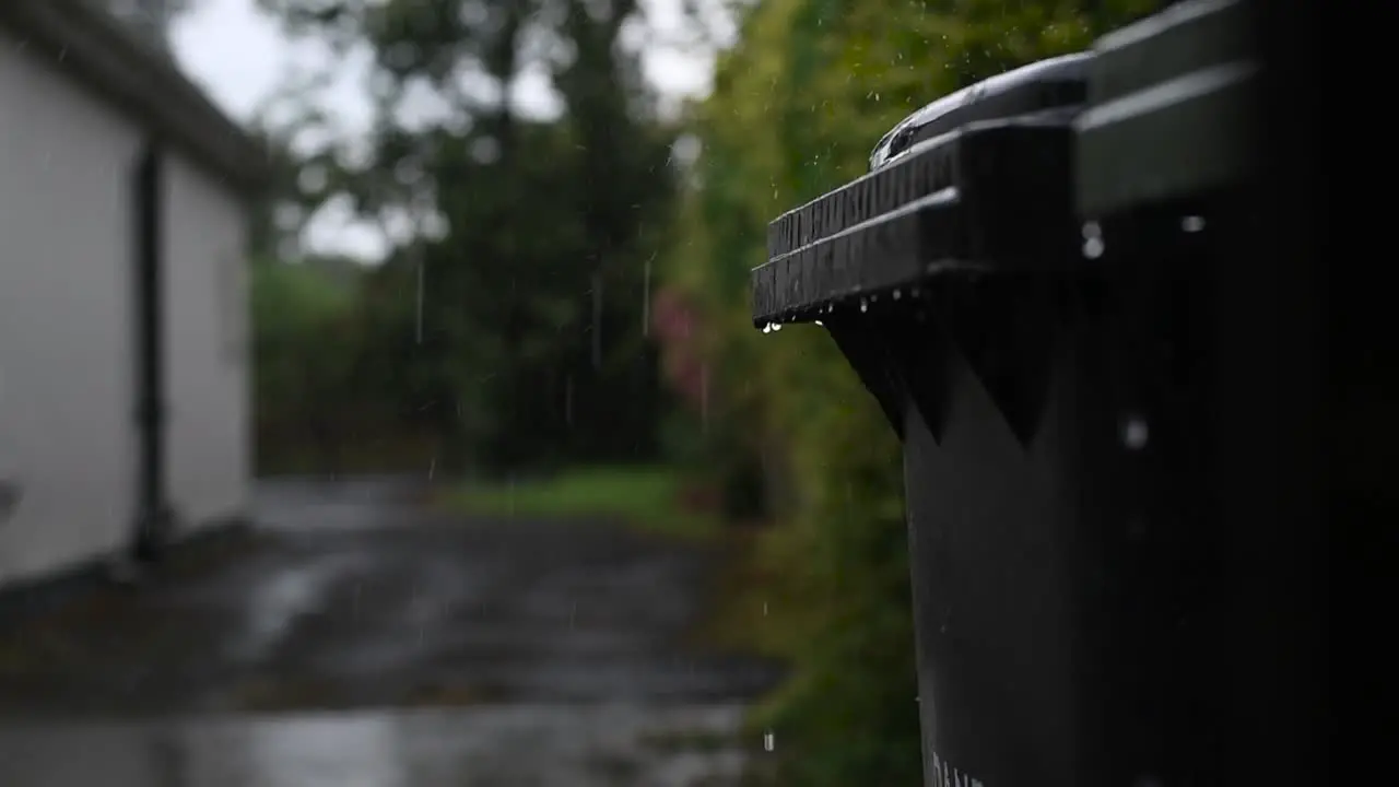 Raindrops dripping off the lids of the wheelie bins in slow-motion