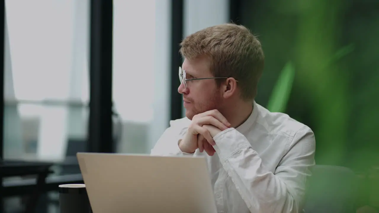 Focused concentrated young businessman sit at desk look at laptop Authentic portrait of young confident businessman looking at camera with laptop in office