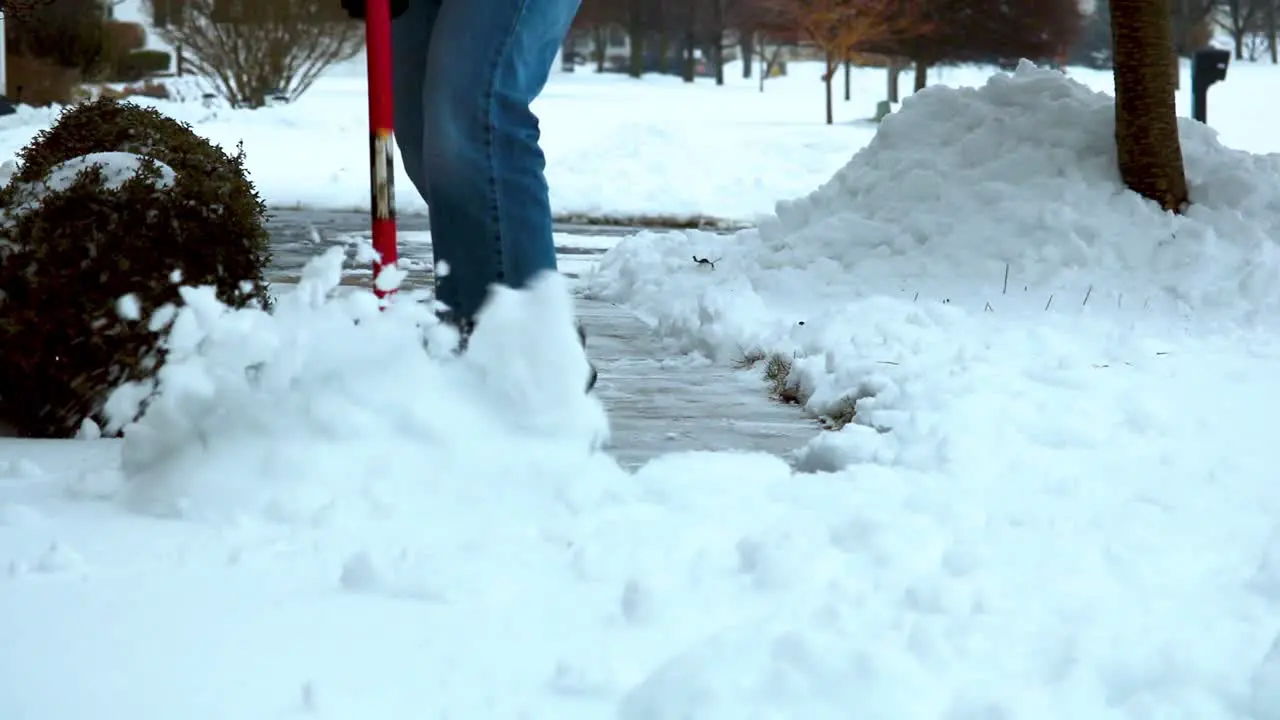 HD slow mo video clip of a man shoveling snow on a concrete sidewalk after a winter storm in cold weather