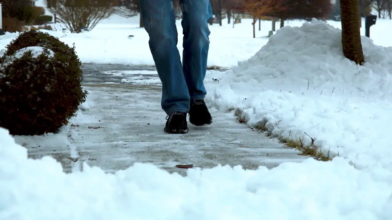 HD video clip of man salting a concrete sidewalk in a suburban neighborhood in Michigan USA in the winter right after a winter storm winter life hack throw some salt on the sidewalk to thaw ice snow