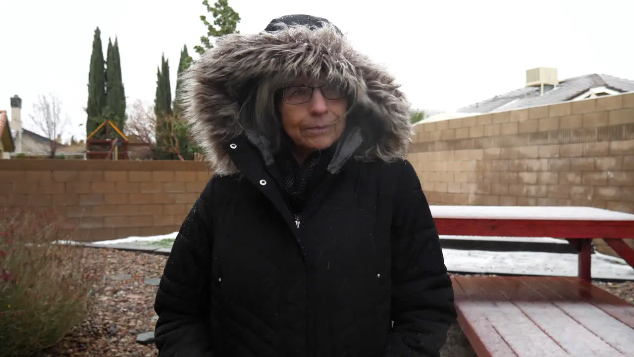 A woman in a warm winter coat walking as snowflakes and hail fall in a freezing cold winter storm SLOW MOTION