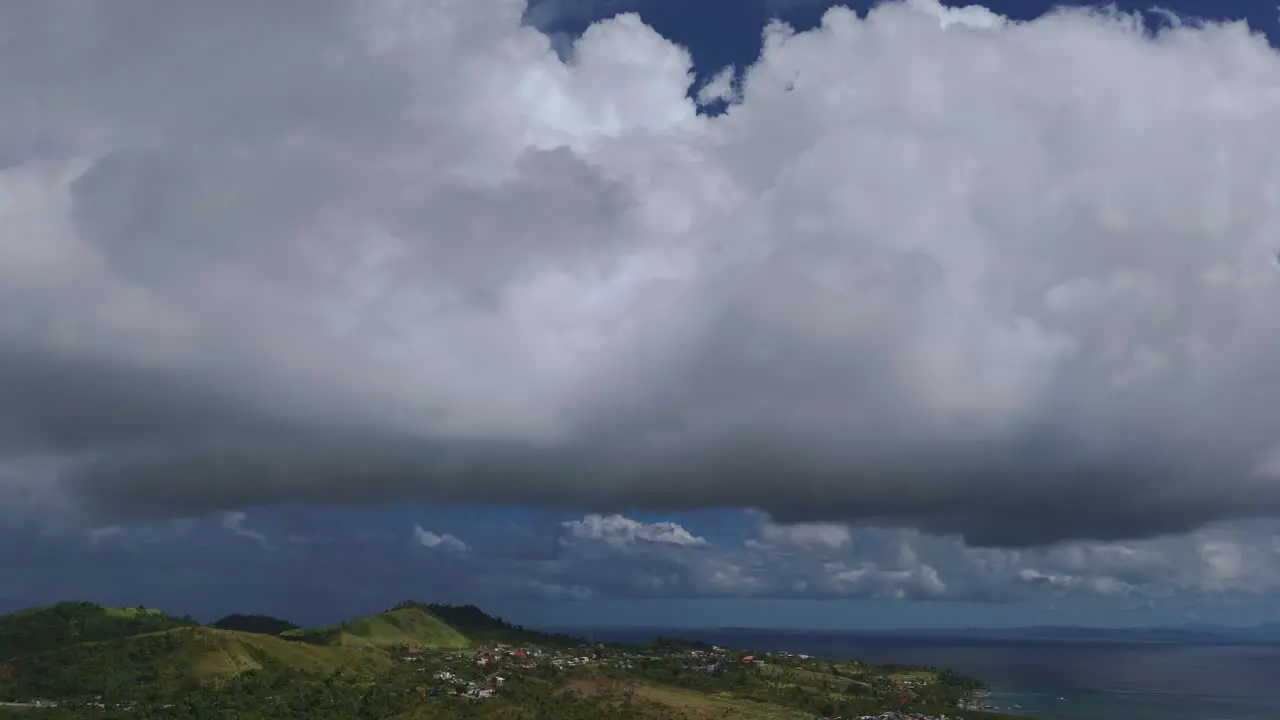 Aerials of a hilly and region with dense Columbus clouds hovering over a city