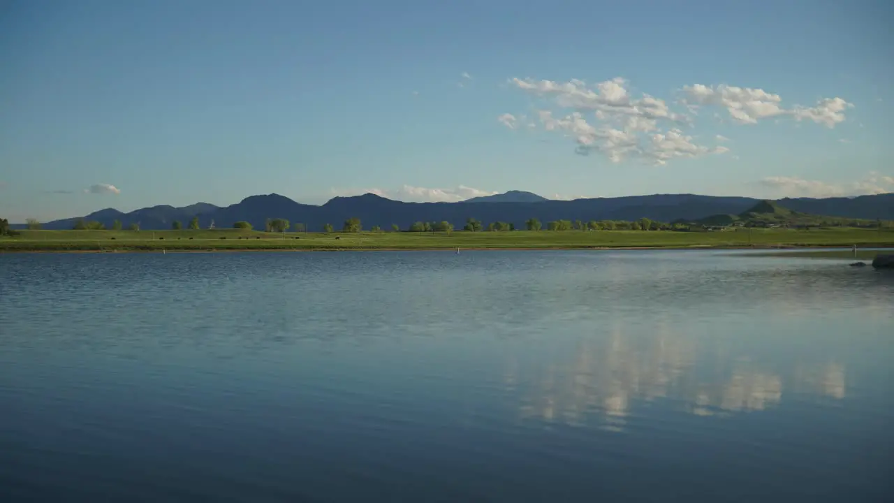 Time lapse of clouds floating over rolling hills and water