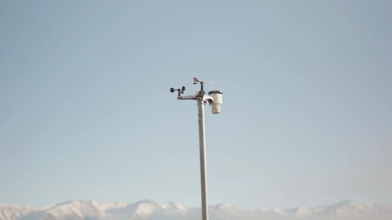 Pole mounted wireless weather station in front of snow-capped mountains