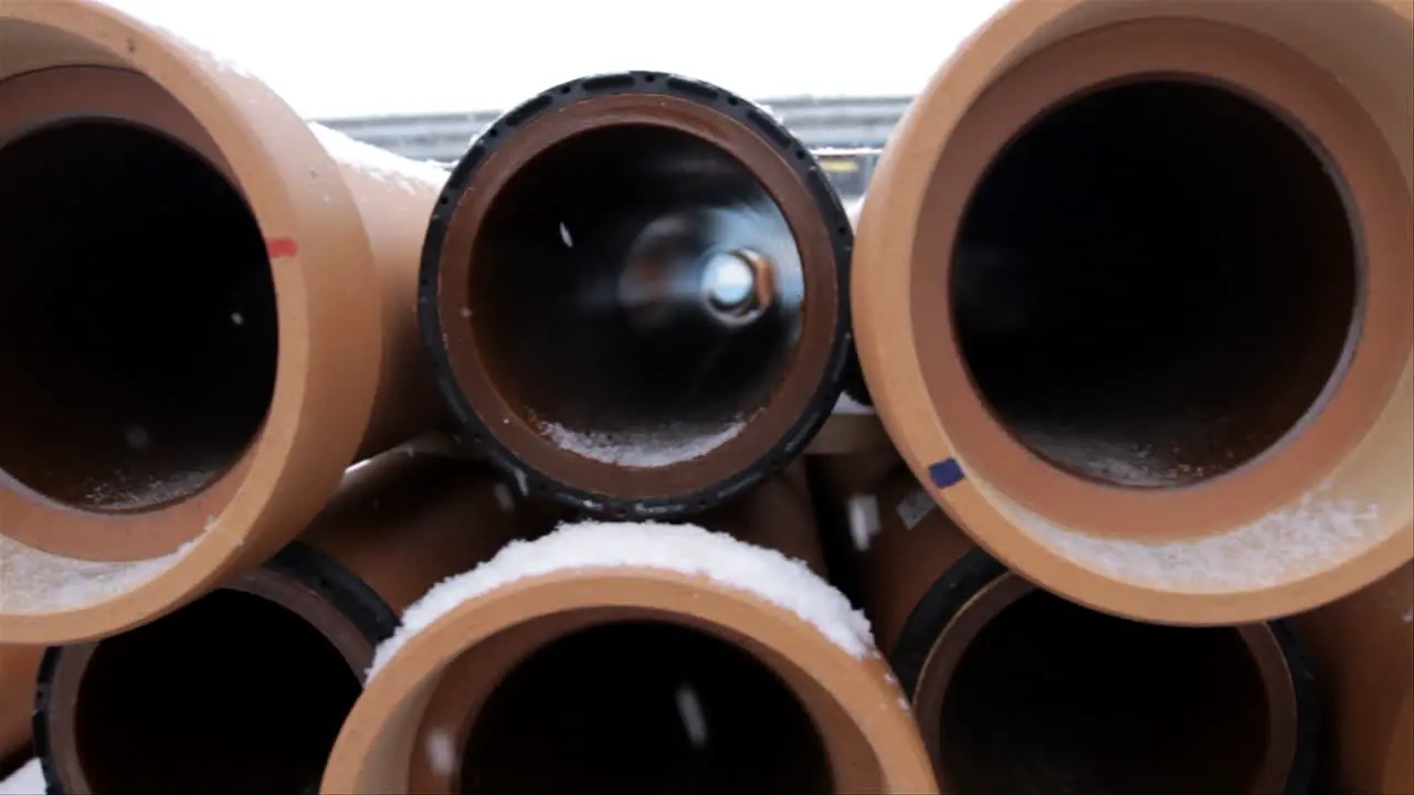 Snow is falling in winter time as we look inside some long brown pipes