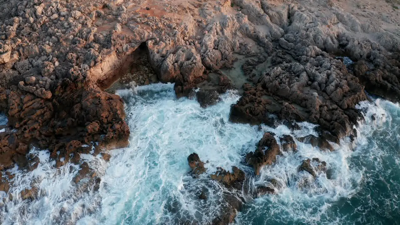 Drone Shot of waves crashing onto shore during sunset and golden hour in Mallorca