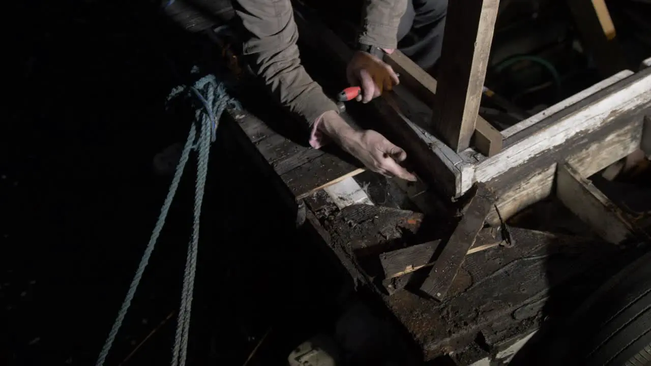 Boat maintenance repair work removing rotten timber at night