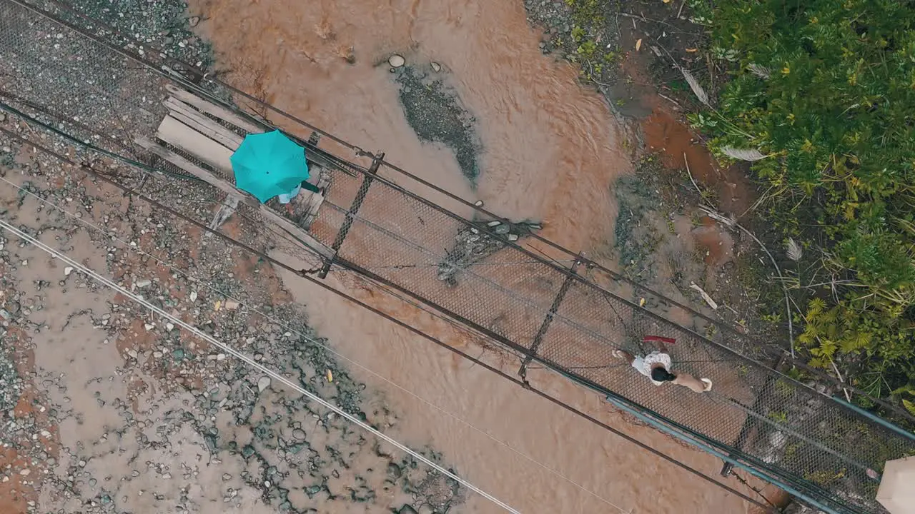 Local residence of Mabini crossing the flooded river by walking on an old rusted bridge