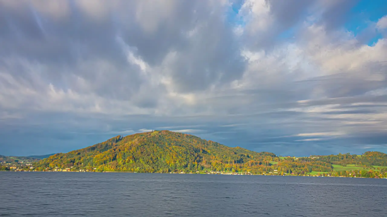 Timelapse clip of the moving clouds and green hill situated near a water body