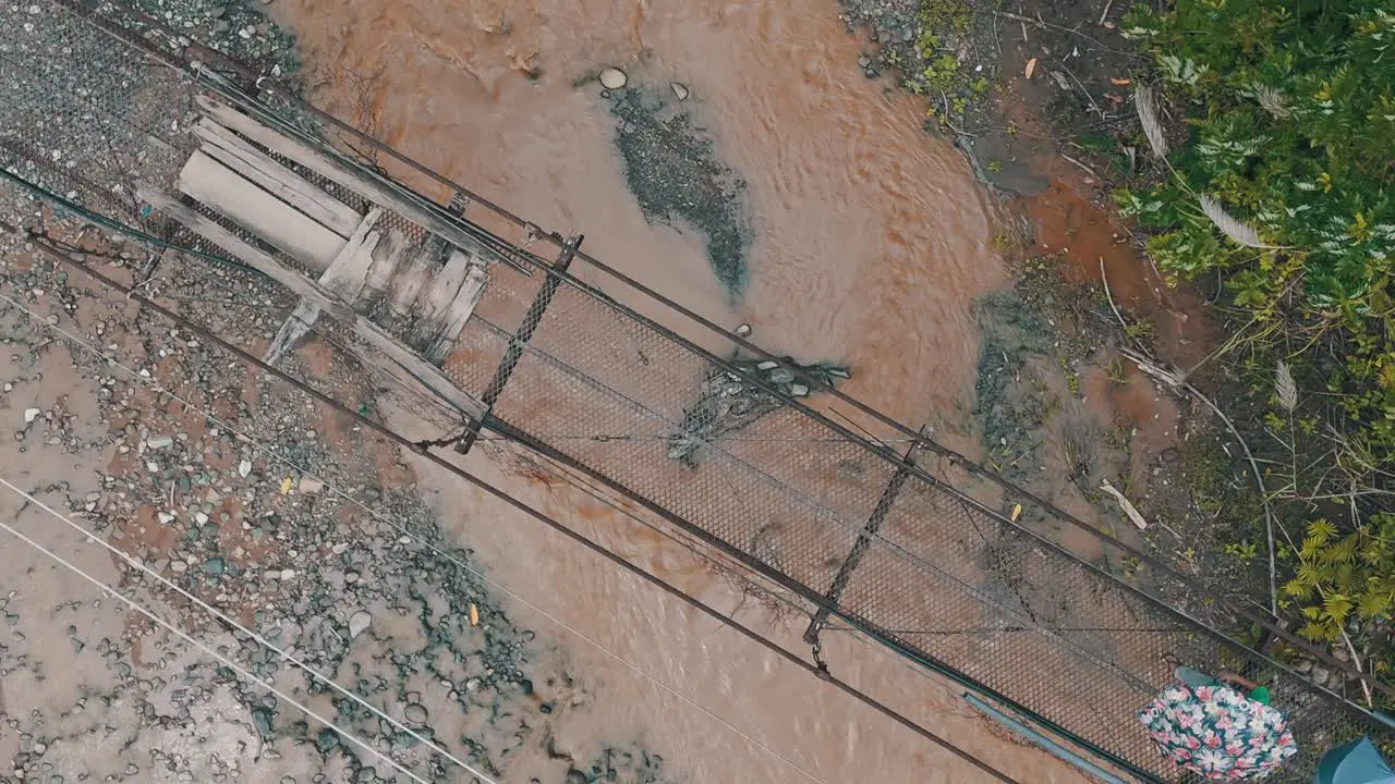 Rural residence crossing a old rusty temporary bridge over the flooded river during rain