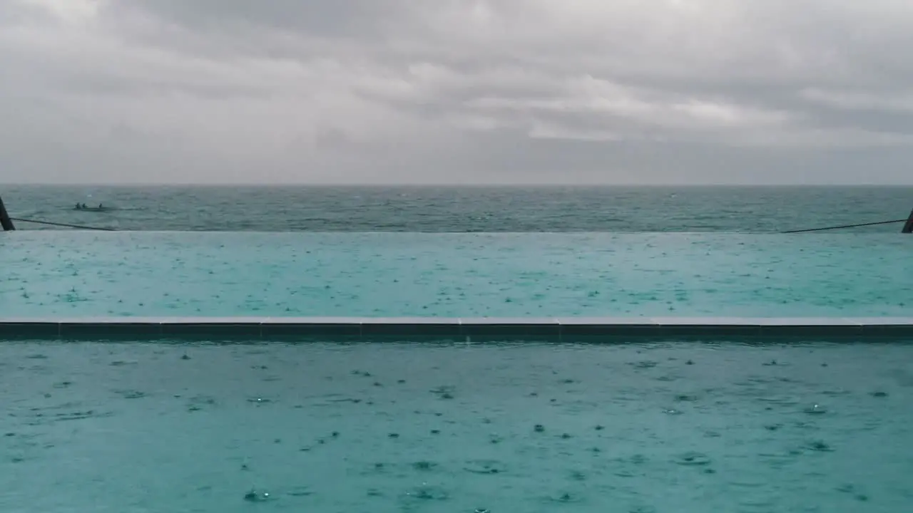 Still clip of rain drops falling on the water surface in a beach side pool