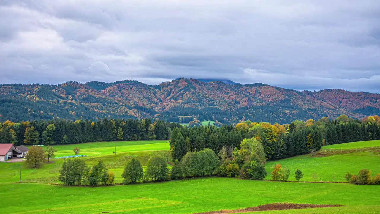 Timelapse footage of the clouds moving above the high mountain peaks and the green landscape in the valley