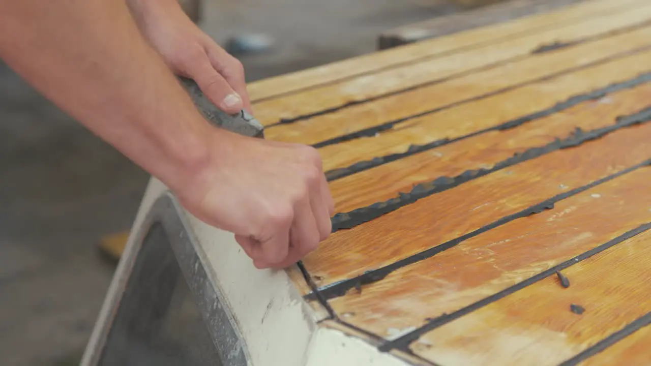 Trimming mastic flashing excess on cabin roof planking of wooden boat