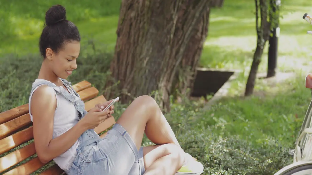 Content girl using smartphone in park