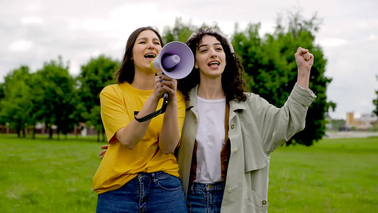 Two Female Friends In A Protest Using A Megaphone