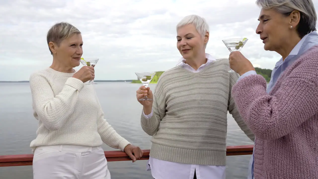 Three Senior Women Having A Drink Close To A Lake 1