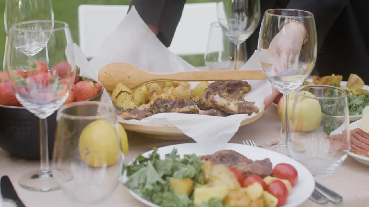 Close Up Of Two Unrecognizable Women Setting Food On A Dining Table For An Outdoor Party In The Park