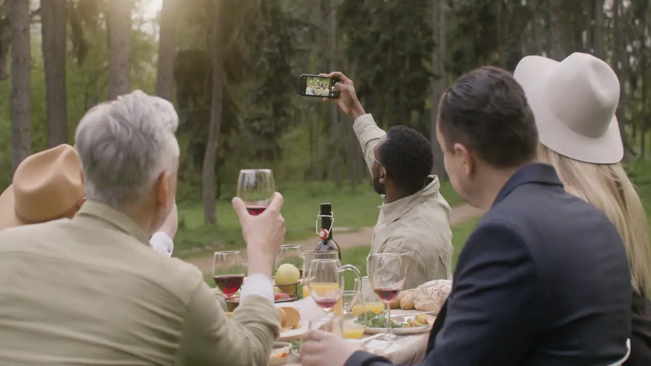 Group Of Middle Aged Friends Taking A Selfie Sitting At Table During An Outdoor Party In The Park