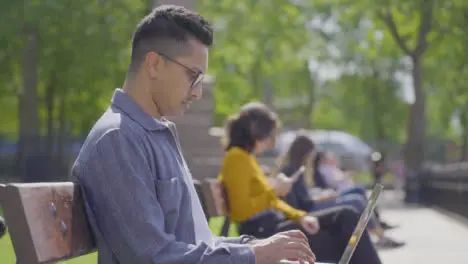 Pull Focus from Man Using Laptop to Woman on Park Bench