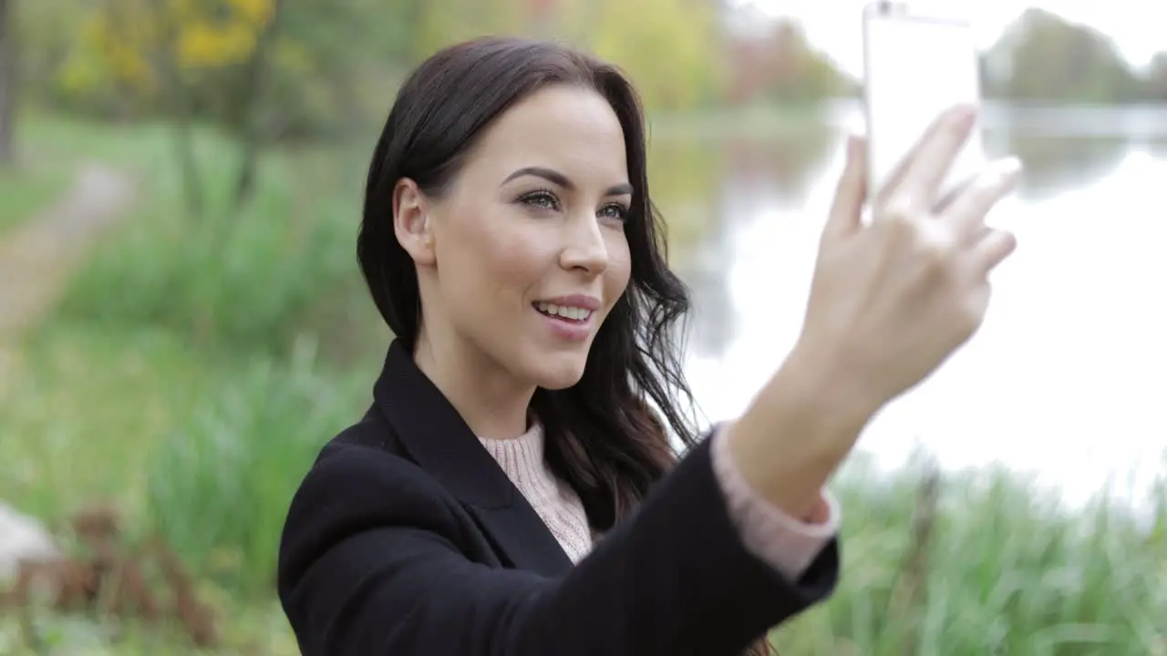 Woman taking selfie near pond