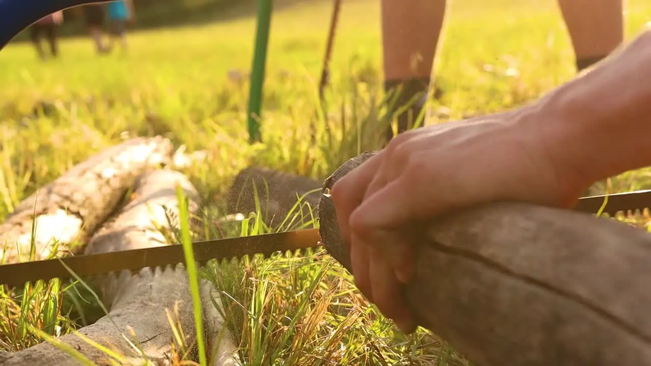 Hand Saws A Log Outdoors During Summer Scout Camp Close Up Slow motion