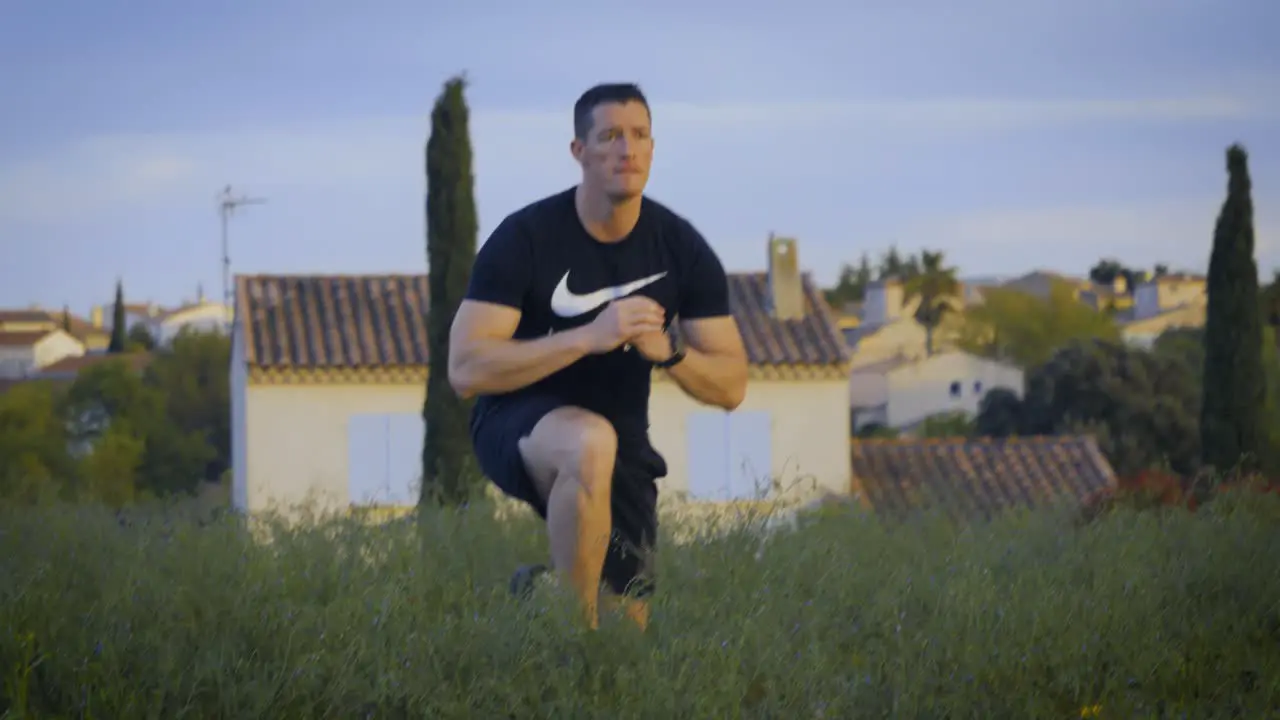 Tracking shot of male athlete making Lunge sidestep outdoors in garden closeup