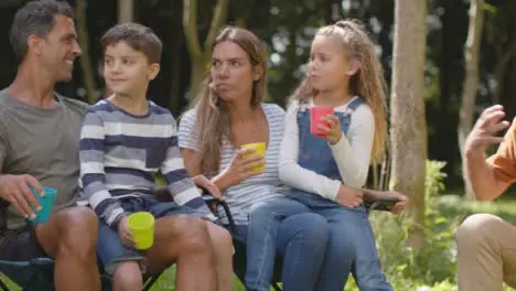 Tracking Shot of Family On Camping Trip Sitting and Talking by Their Tents 01