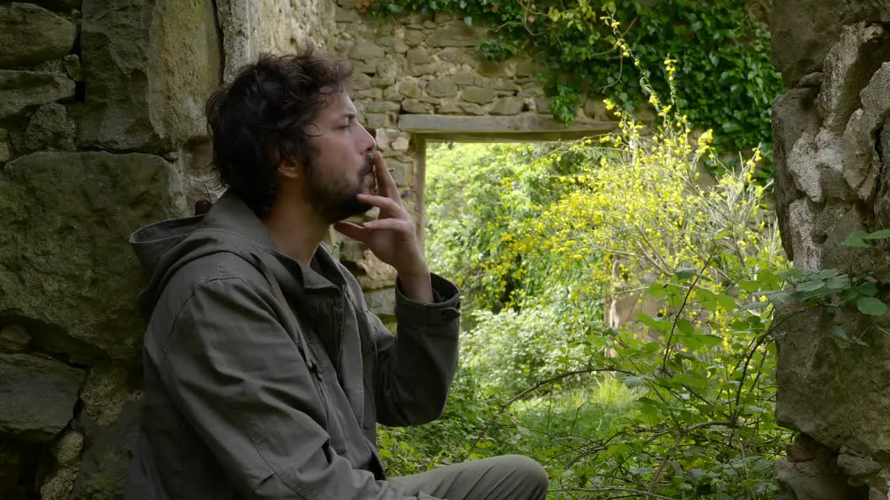 Portrait of a man sitting in some old ruins stopping to enjoy a cigarette break now considered an antisocial habit