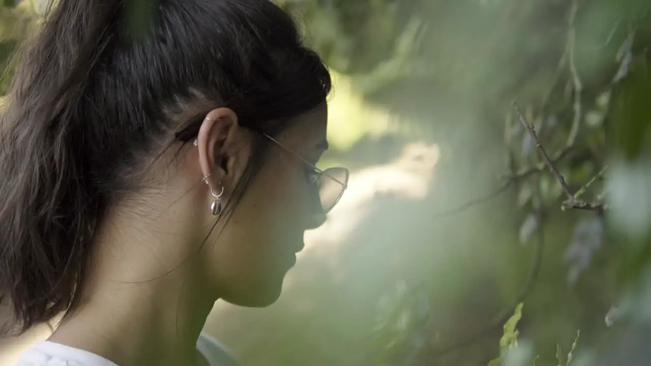 Rotating shot of a model looking at the new life growing on the low-hanging branches