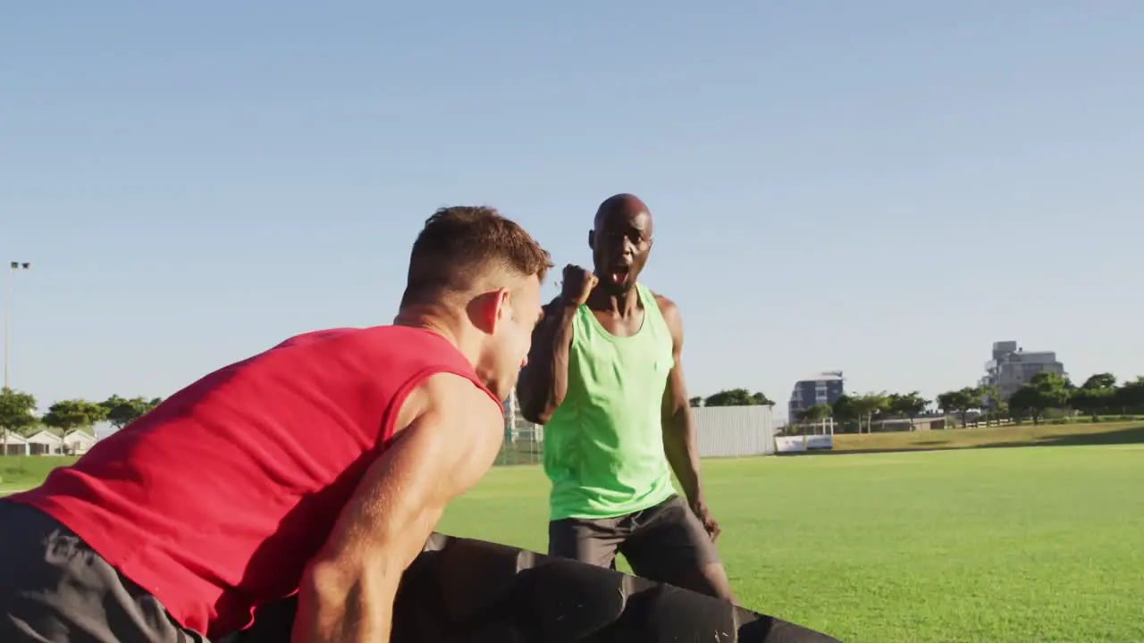 Diverse fit men cross training outdoors with tire