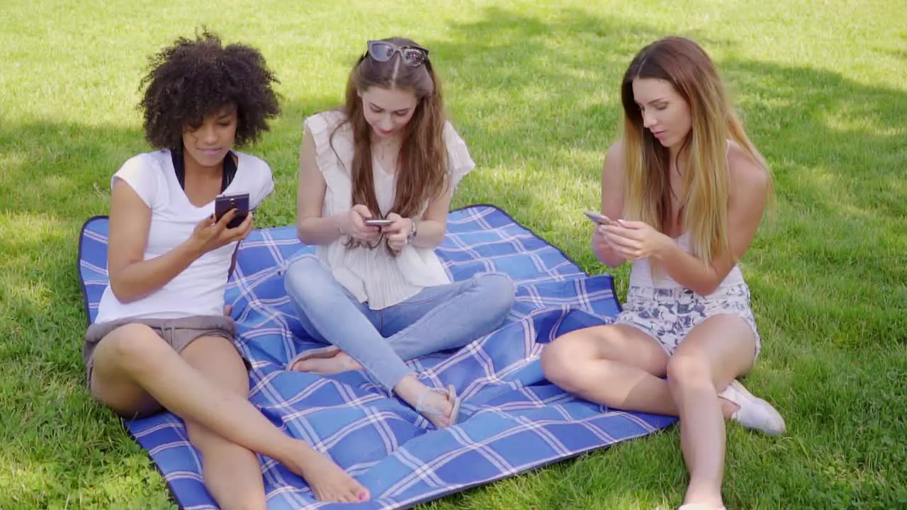 Women browsing smartphones in park