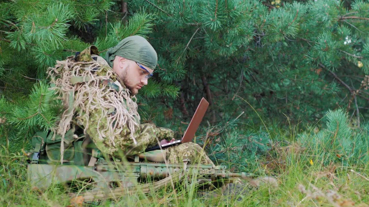 Armed Men In Camouflage Sitting In The Woods It Uses Laptop