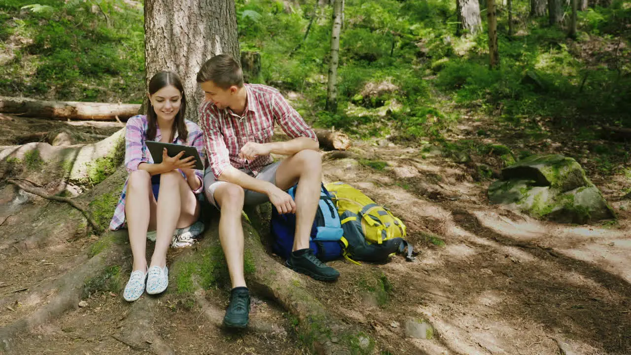 A Young Couple Of Tourists Are Resting Under A Tree