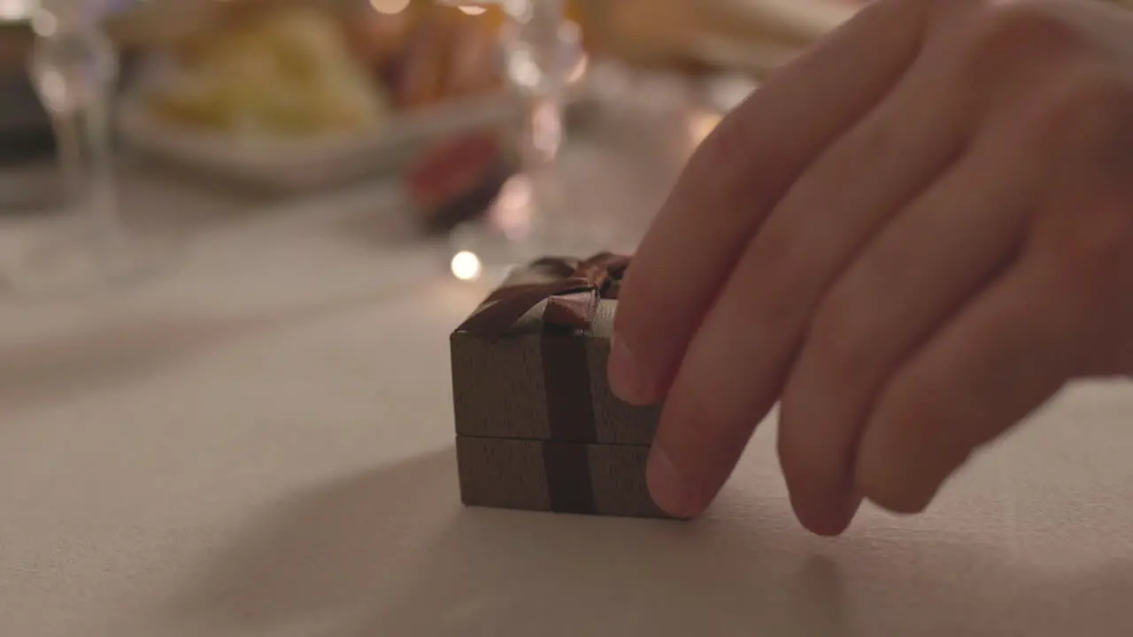 Close Up Of Unrecognizable Man Giving A Ring Box To Woman While Sitting At Romantic Dinner Table