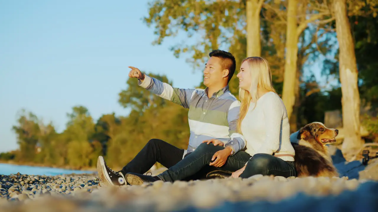 Couple With Dog by a Lake at Sunset