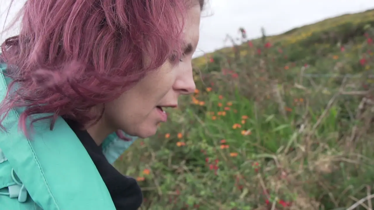 Close up Slow motion shot of a beautiful girl woman with wind in her hair trying a blackberry in the wild that puts a smile on her face