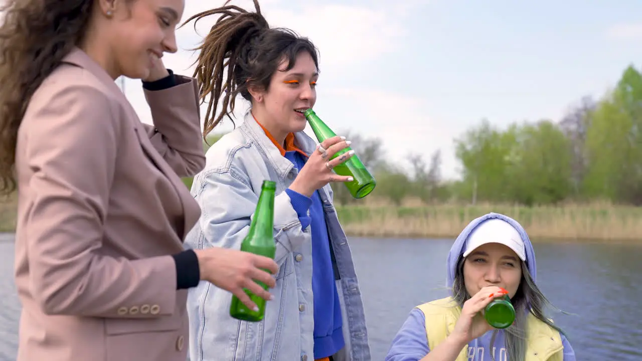 Four Women Toasting And Drinking Beer Next To The River