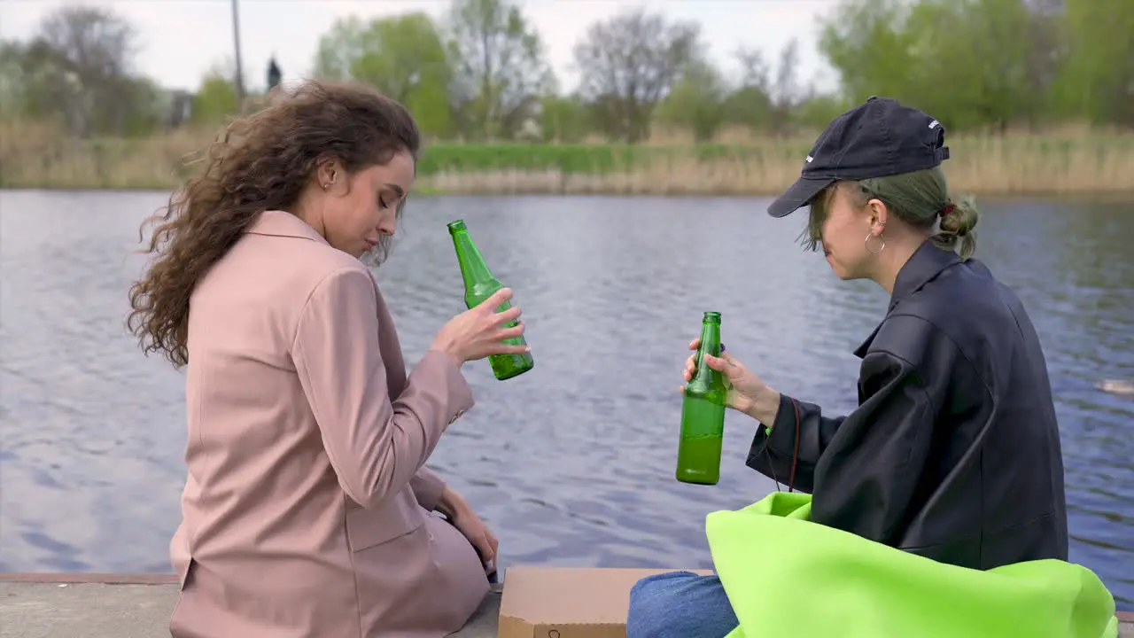 A Pair Of Friends Talking And Drinking Beer On The Riverside