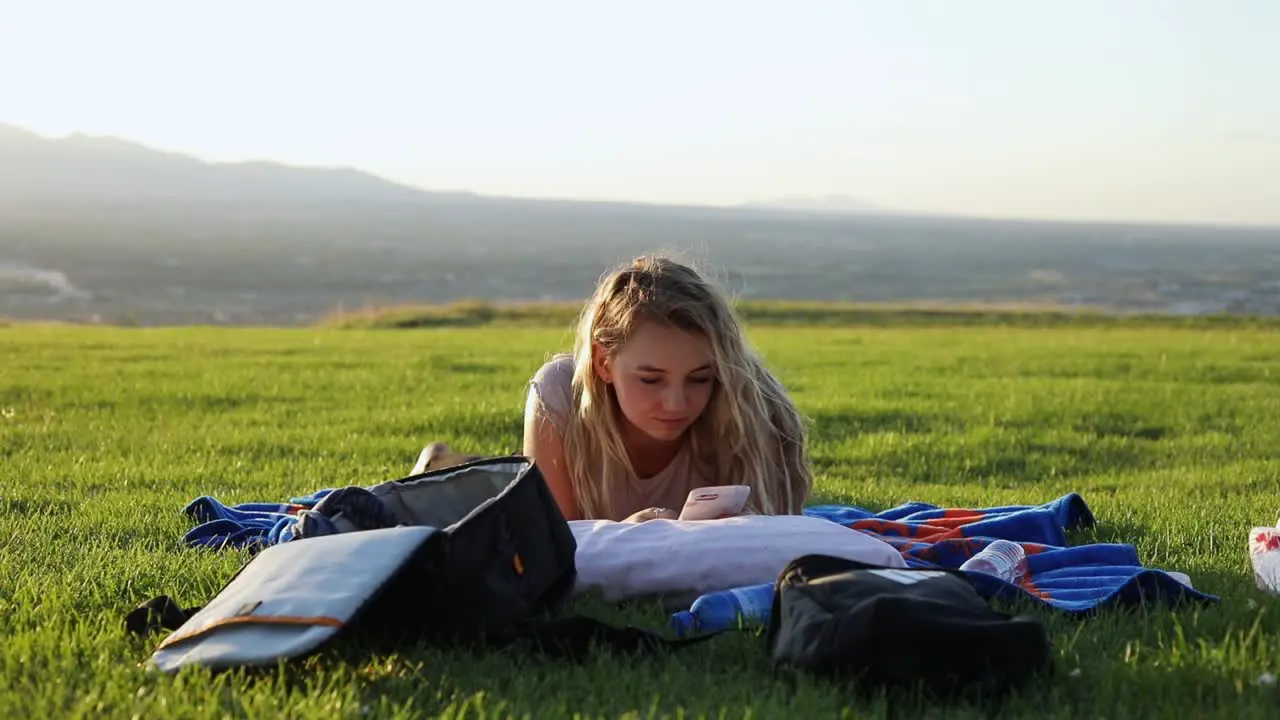 Shot of a beautiful young woman laying on a blanket on the grass at a park