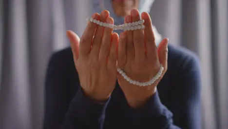 Close Up Of Muslim Woman Wearing Hijab Praying Holding Prayer Beads At Home 2