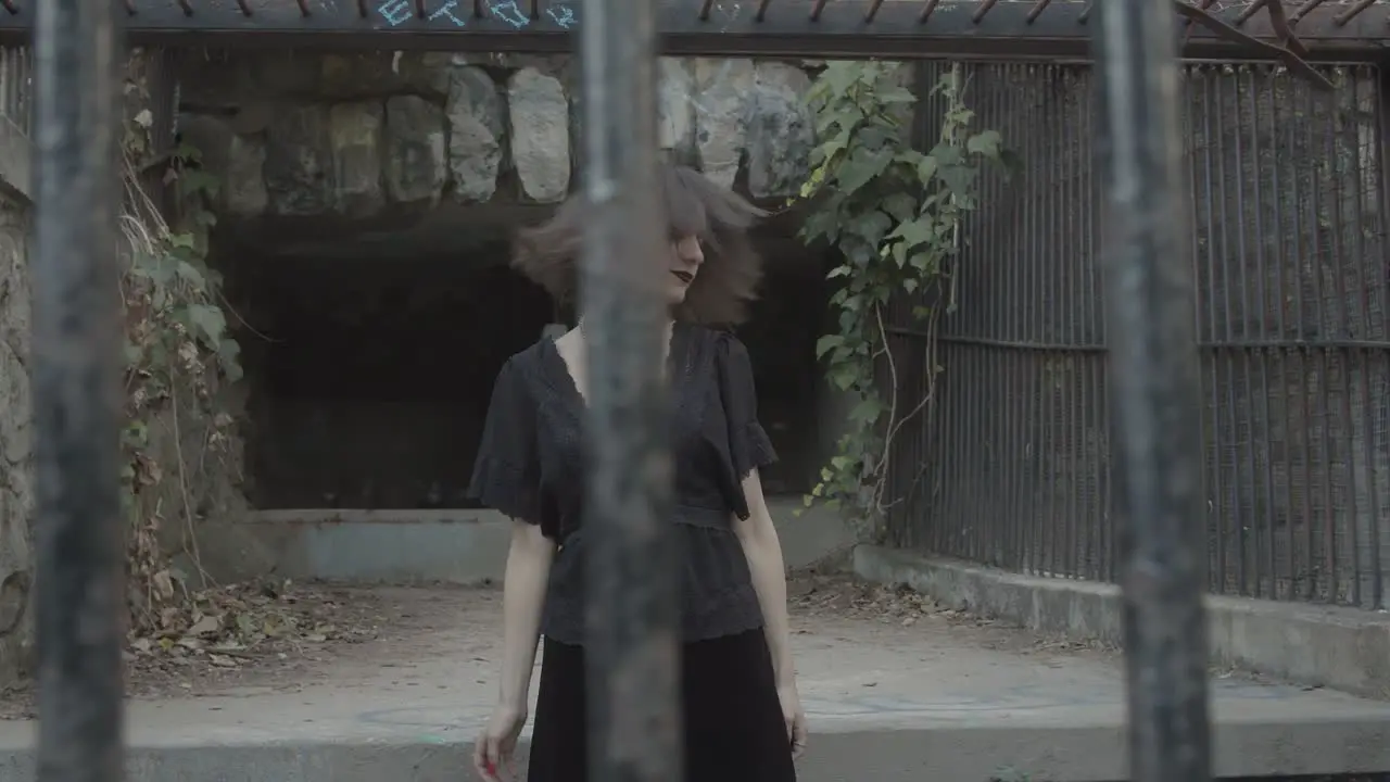 Slow motion young woman shaking her hair side to side inside metal cage in abandoned zoo cage