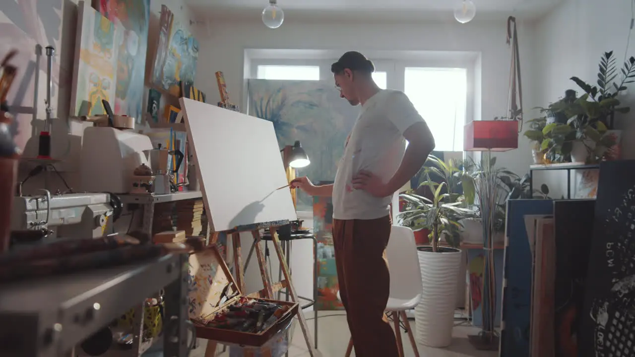 Male Artist Drawing Picture on Canvas in Studio